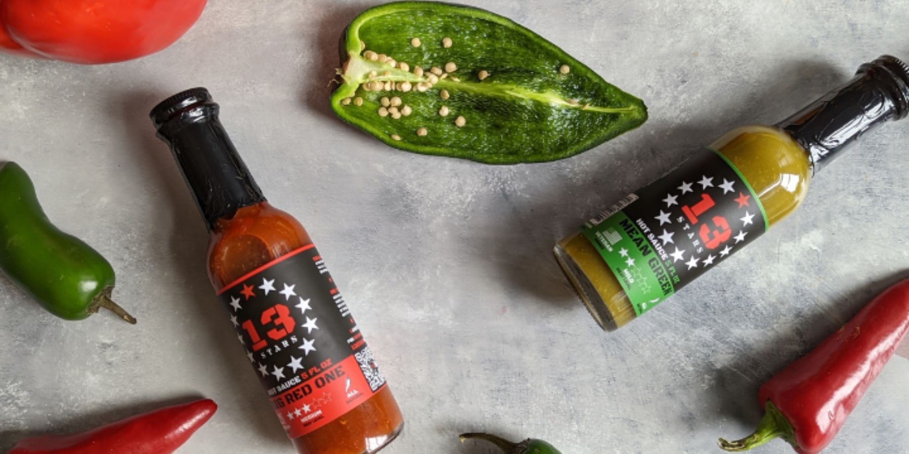 13 Stars Hot Sauce bottles arranged on a white background with ingredients around it