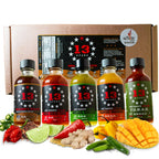 Five bottles of 13 Stars Hot Sauce arranged in front of a cardboard gift box, with colorful ingredients including red chilies, lime, ginger, mango, and green chilies placed in front. A Scoville Winner badge is visible on the box.