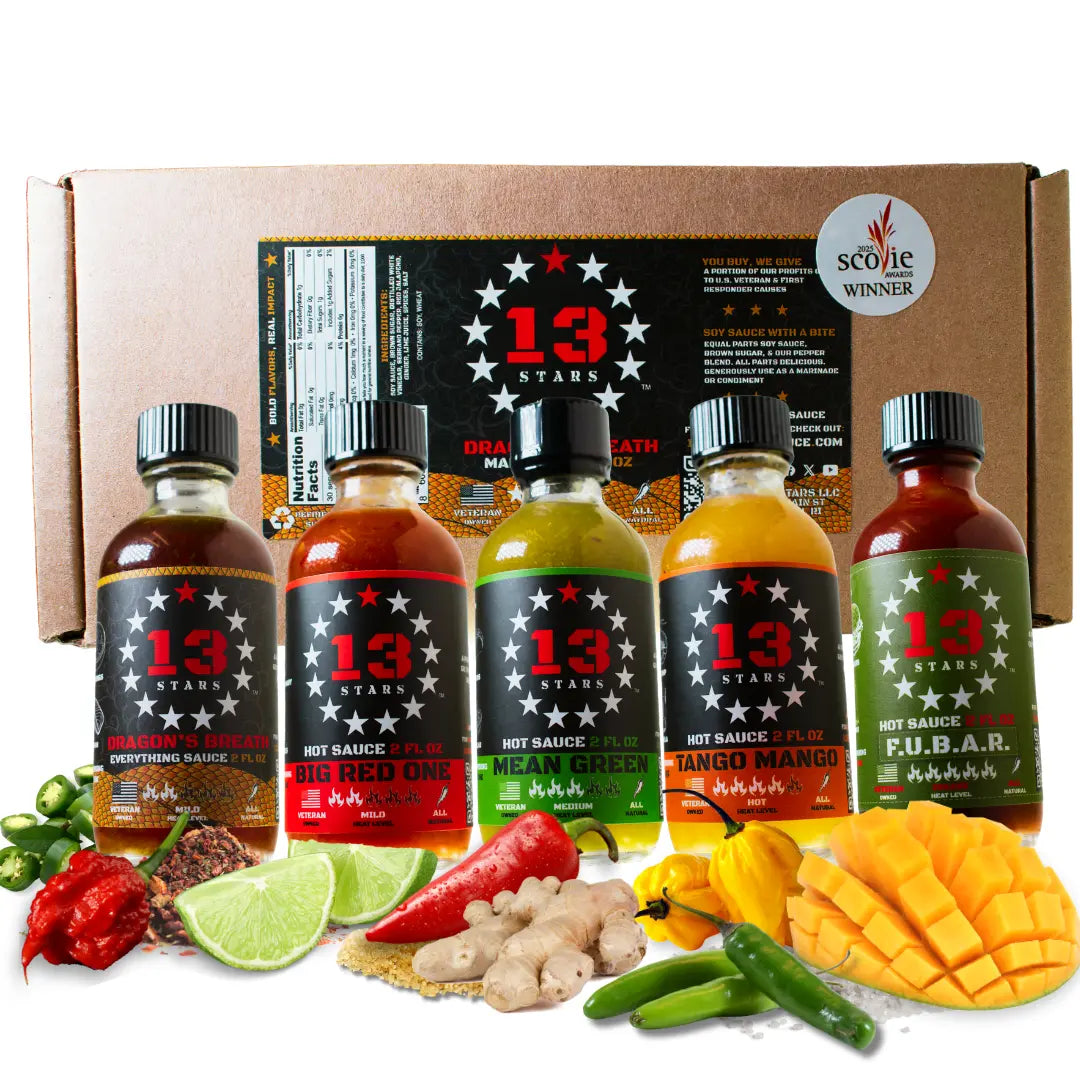 Five bottles of 13 Stars Hot Sauce arranged in front of a cardboard gift box, with colorful ingredients including red chilies, lime, ginger, mango, and green chilies placed in front. A Scoville Winner badge is visible on the box.